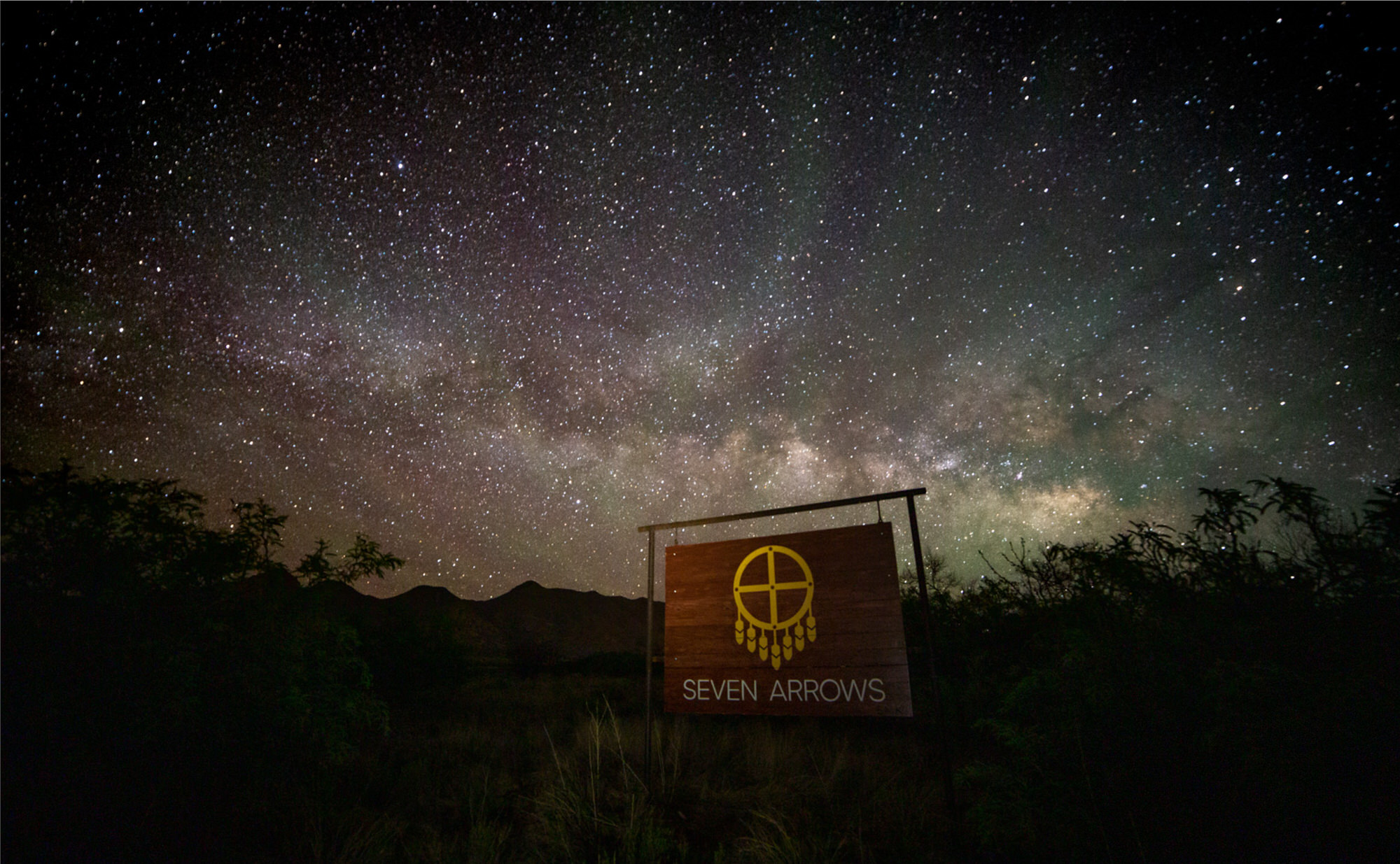 Seven Arrows sign under a Milky Way night sky